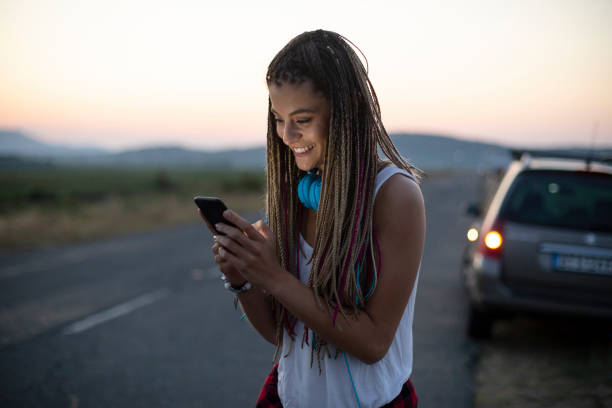 istock Smiling young woman using smart phone on country road 1096476656