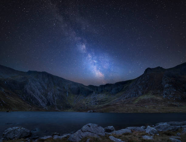 Digital composite Milky Way image of Beautiful landscape image of Llyn Idwal and Devil's Kitchen in Snowdoina Stunning vibrant Milky Way composite image over Beautiful landscape image of Llyn Idwal and Devil's Kitchen in Snowdoina snowdonia stock pictures, royalty-free photos & images