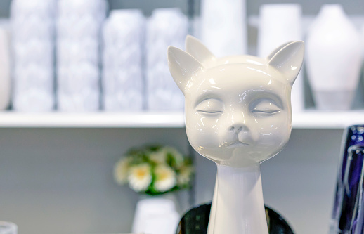 White ceramic figurine of a cat with eyes closed.