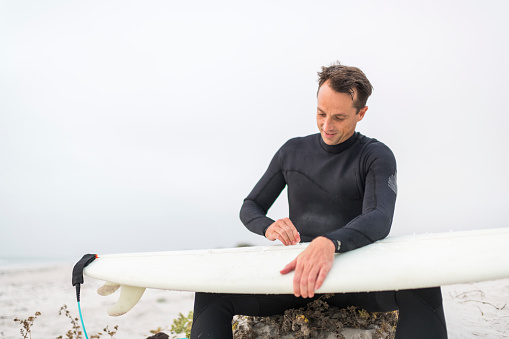 Low angle view of a surfer waxing his board before going surfing