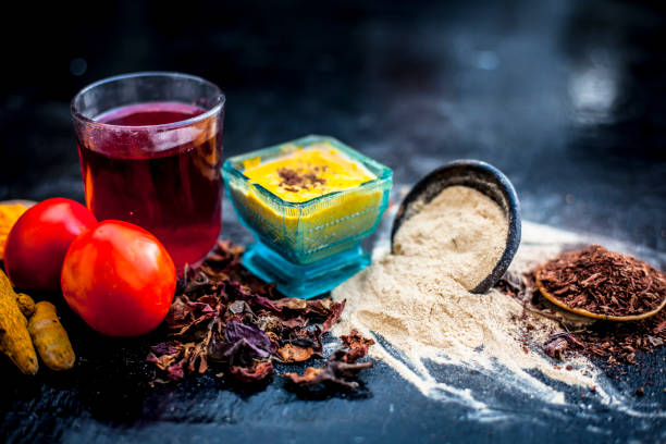 Close up of herbal face pack of tomato and turmeric with sandal wood,fuller's earth or mulatni mitti or mulpani mitti on wooden surface used to make your face glow in glass bowl with raw ingredients. cerca de hierbas mascarilla purificante de tomate y cúrcuma con madera de la sandalia, tierra de batán o mitti mulatni o mulpani mitti en la superficie de madera utilizado para hacer la cara brillan en recipiente de vidrio con ingredientes crudos.