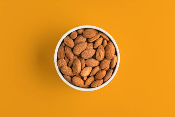Almonds in a bowl on yellow background