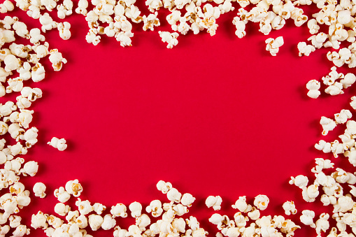 Frame with tasty fresh popcorn on red background