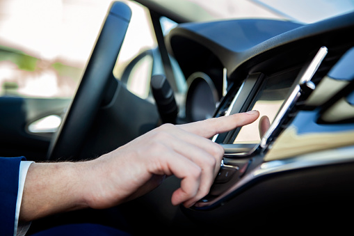 Man hand touching the LCD screen in the car. Using navigation system on dashboard of modern car