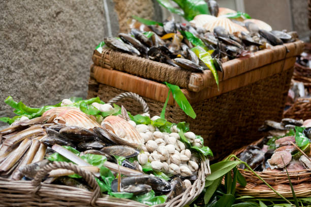 Scallops, cockles, mussels and razor clams at a street market. Close-up view of display of scallops, cockles, mussels and razor clams  in baskets at a street market. Decoration in a Traditional festival in Muros, A Coruña province, Galicia, Spain. mollusca stock pictures, royalty-free photos & images