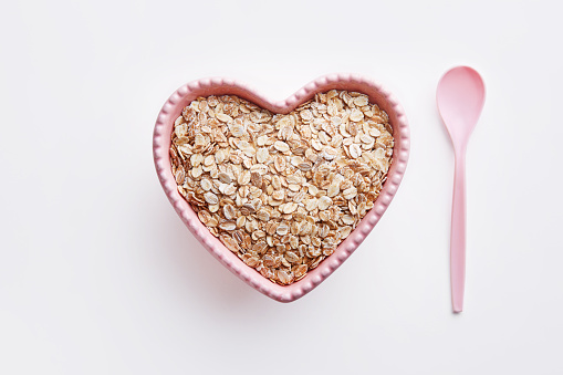 Oat meal in a hart shaped bowl isolated on a white background viewed from above. Top view. Healthy, fresh, home made cereals breakfast