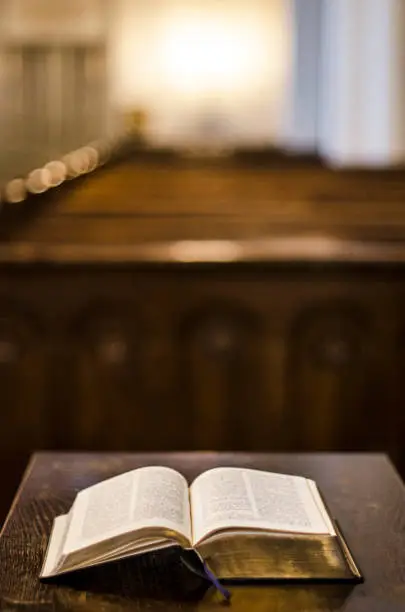 Holy bible laying on a tabel in front of the benches in the church