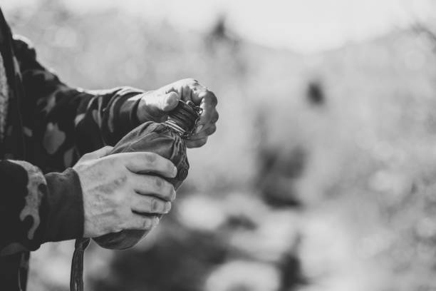 aluminum canteen in hands of soldier, monochrome effect - military canteen imagens e fotografias de stock