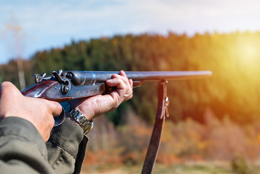 Hunter with retro shotgun aims at the target. Hunting season.