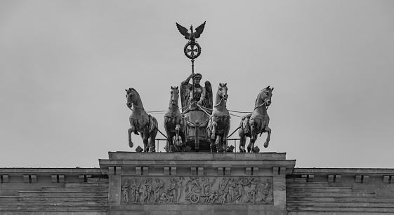 A black and white picture of the statue at the top of the Brandenburg Gate, in Berlin.