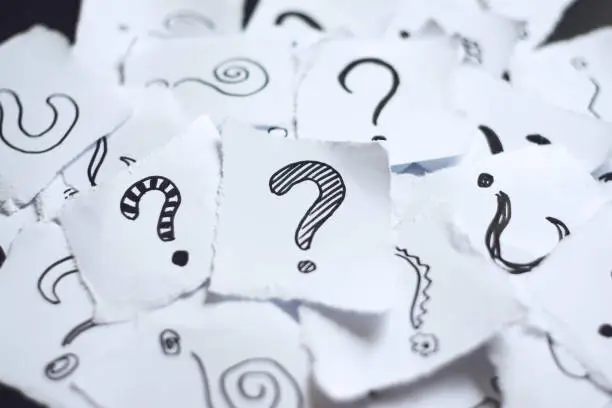 Photo of Many question marks on white papers. Doodle drawn question marks on scraps of paper. Choice, decision making, assortment concept