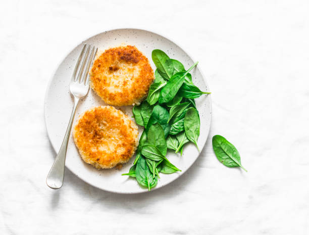 istock Potato bread crumbs baked cakes with spinach on a light background, top view. Delicious vegetarian lunch 1096547898