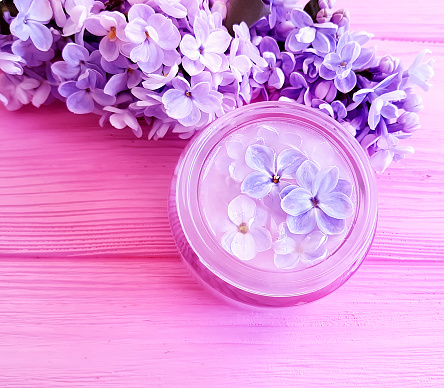 cosmetic cream, lilac flower on wooden background