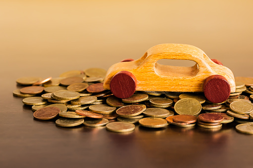 Wooden car on group of coins