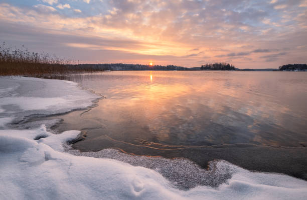 scenic winter landscape with frozen lake and sunset at evening time in finland - cold frozen sea landscape imagens e fotografias de stock