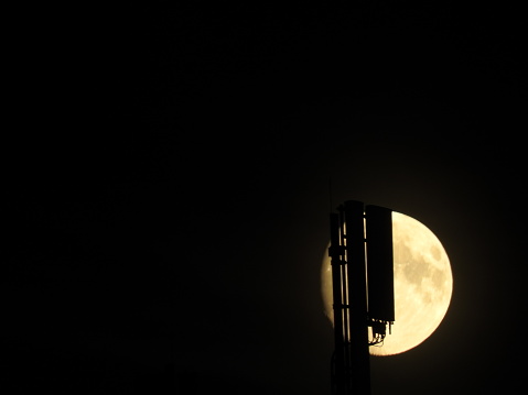 Silhouette of antenna in night in front of full moon. GSM 5G.