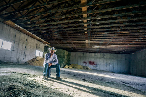 istock Inside a barn, a desperate looking man sitting all by himself on a bucket. 1096563948