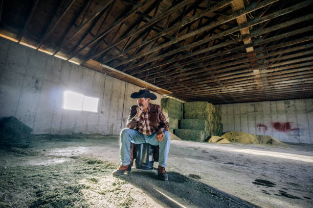 istock Inside a barn, a desperate looking man sitting all by himself on a bucket. 1096563954