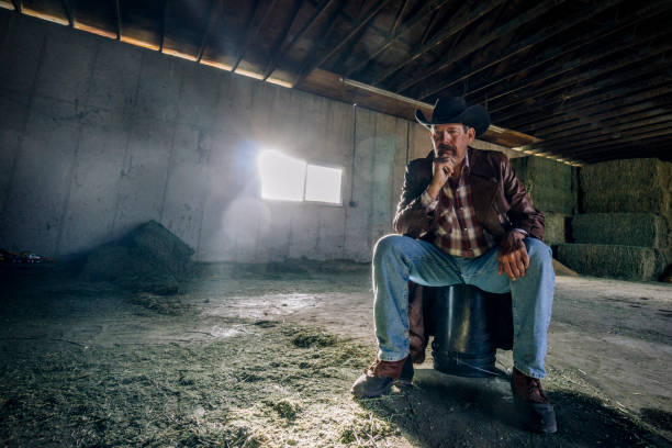 istock Inside a barn, a desperate looking man sitting all by himself on a bucket. 1096563978