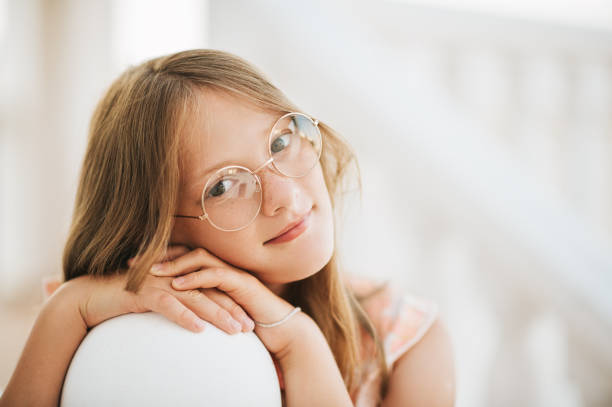 Outdoor portrait of beautiful young girl wearing glasses, leaning head on hands, close up image stock photo