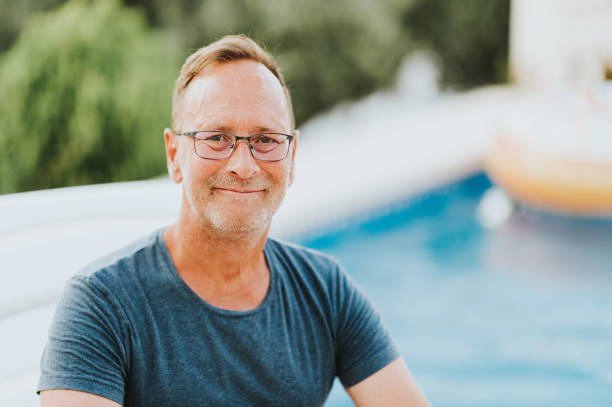 Outdoor portrait of 50 year old man resting by the pool stock photo
