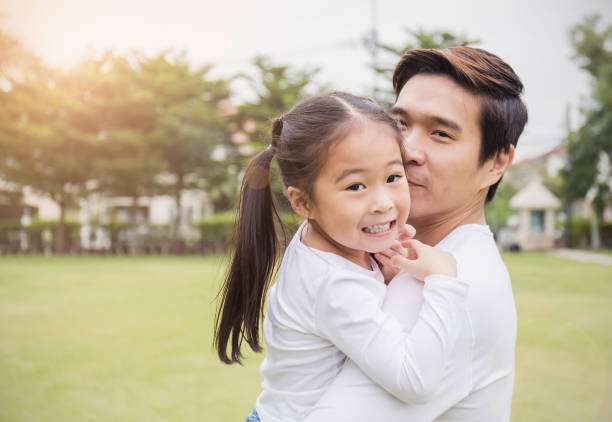 Portrait of happy asian father and daughter in the park. Happy family green spring or summer father's day together environment concept Portrait of happy asian father and daughter in the park. Asian man and little toddler girl carry cuddle and hug in the park. Happy family green spring or summer fatherâs day together environment concept korean baby stock pictures, royalty-free photos & images