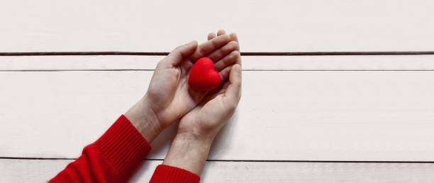 istock Valentine's day concept.Woman hands red heart on white table 1096612740