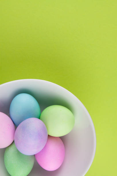 istock Overhead view of brightly painted easter eggs in a white bowl on green background 1096625776
