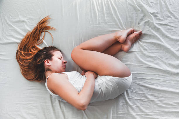 istock Young woman lying down in pain on the bed 1096635766
