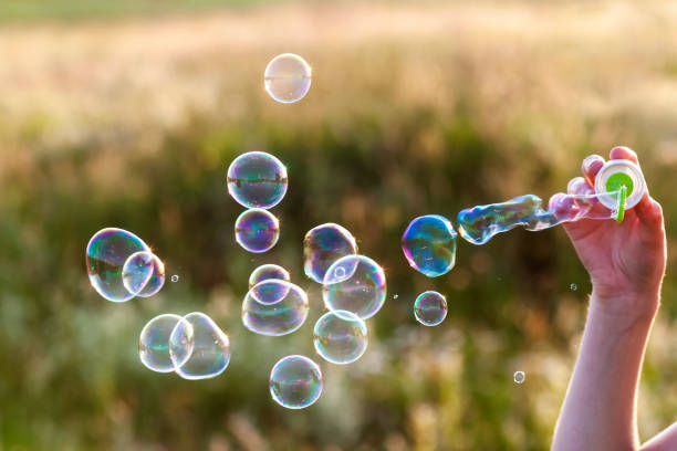 istock Womans hand with blowing colorful soap bubbles at sunset. 1096640972
