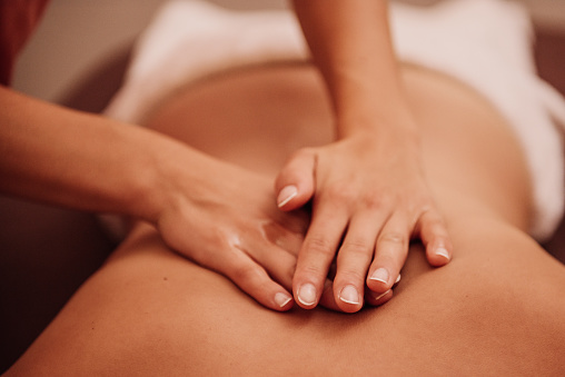 woman getting a back massage at a spa \nPhoto taken indoors with stobe light