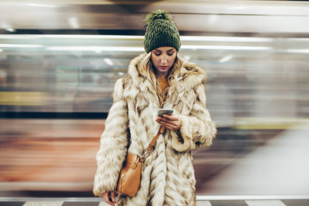 ragazza triste che usa il telefono mentre si trova su una piattaforma della metropolitana - train subway station people subway train foto e immagini stock