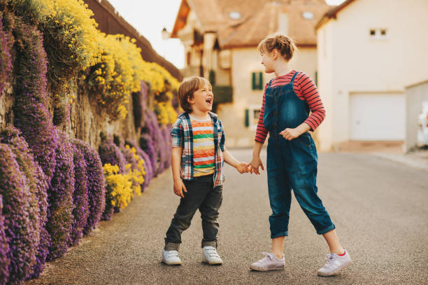 istock Two cute happy young kids playing together outdoors on a nice sunny evening, holding hands. Small brother and big sister spending time together 1096689028