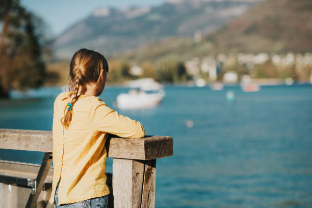 little kid girl admaring annecy lake in erly spring, family travel with children, back view - hot couture imagens e fotografias de stock