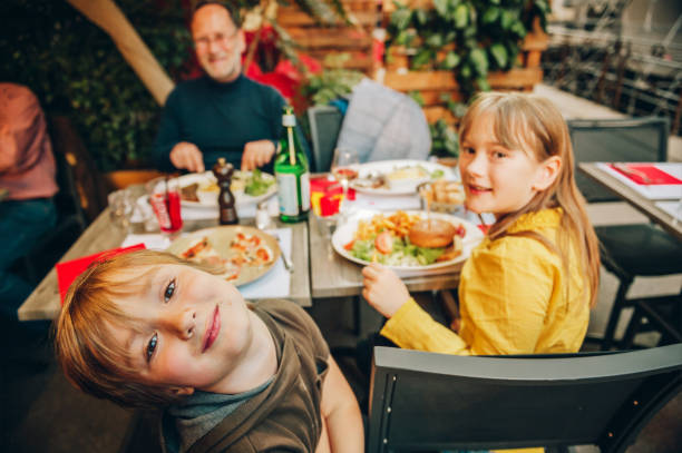 happy family eating hamburger with french fries and pizza in outdoor restaurant - burger hamburger large food imagens e fotografias de stock