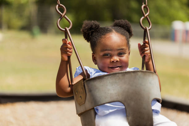 cute little african american kołysząc się w parku. - child swinging playground african descent zdjęcia i obrazy z banku zdjęć