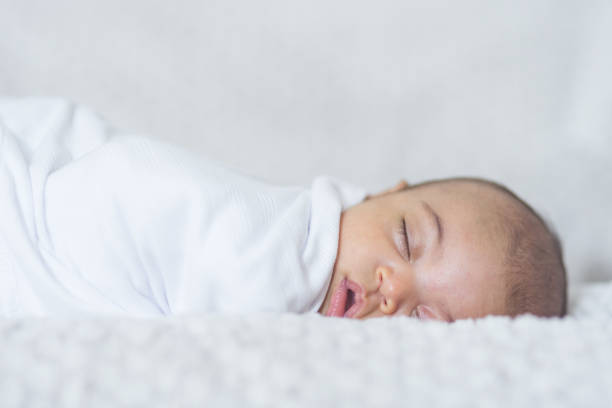 Newborn sleeping baby A beautiful newborn interracial baby lays swaddled and sleeping in her hospital bassinet. Her eyes are closed peacefully and she looks like she is having pleasant dreams. biracial newborn stock pictures, royalty-free photos & images