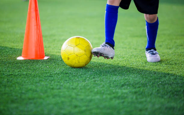 istock Kid soccer player control ball around cone maker for soccer training 1096744574
