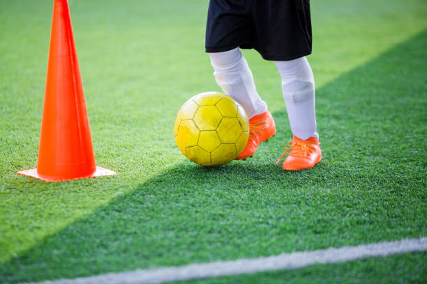 istock Kid soccer player control ball around cone maker for soccer training 1096744576