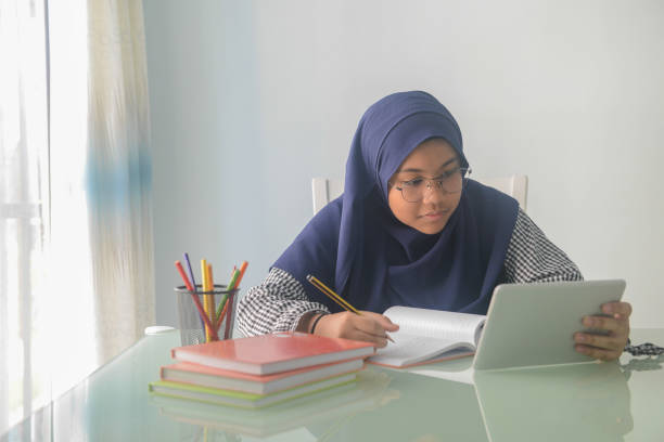 istock An Asian 14 year old girl doing homework on dining table at home. 1096780354
