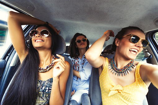 Three happy women singing in a car in a roadtrip