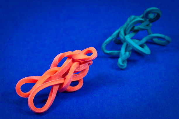 vecchio e nuovo elastico intrecciato su sfondo blu - flexibility rubber rubber band tangled foto e immagini stock