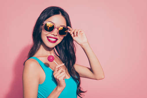 Close-up portrait of nice cheerful cheery glad lovely sweet adorable charming glamorous wavy-haired lady with tasty yummy sugary lolly pop red lips eyeglasses eyewear isolated over pink background