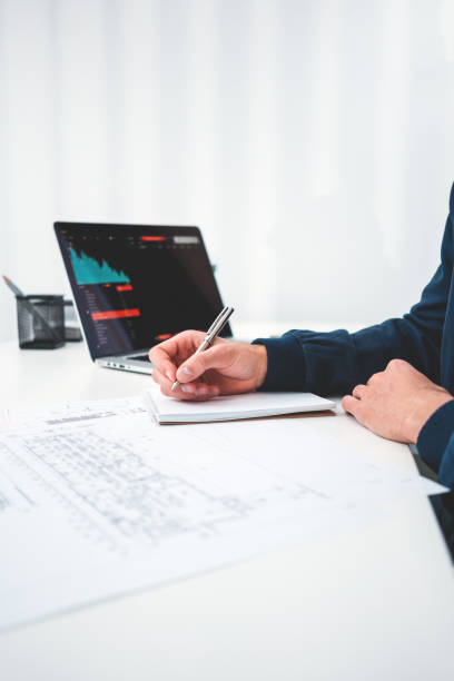 istock Young architect designer using notepad and laptop and analyze drawing plan whine sitting by the table in office space. Engineer sitting at desc and work with buliding drawing. Vertical 1096809918