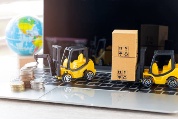 istock Mini forklift truck load cardboard boxes with symbol and stack of coins on laptop keyboard with globe near by. Logistics and transportation management ideas and Industry business commercial concept. 1096812444