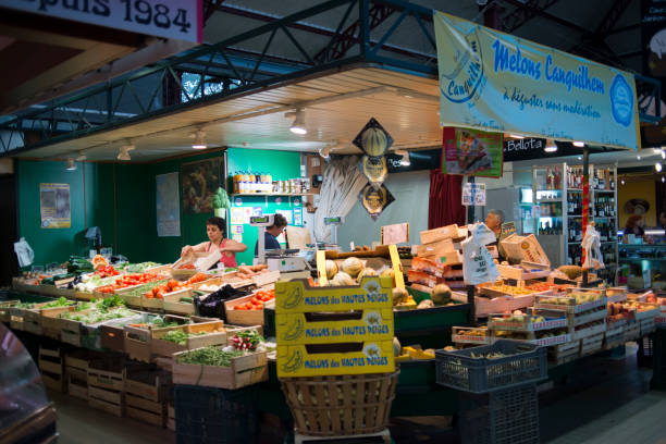 Narbonne Narbonne, market fruits and vegetables shop. France. Much more than a market, the Narbonne Halles are one of the nerve centres of the city. Built in 1901, this vast market hall is still active and more animated than ever before. Its metal framework shelters nearly seventy food businesses: charcutiers, butchers, pastry-makers, bars, greengrocers, and restaurants, including the storied "Chez Bébelle" "u2026"nThis unique gathering place is completely a part of local culture. In the aisles between the stalls, they say that the market has a soul. A warm, bustling spirit."nAnd 2,800 square metres of enticing fragrances "u2013 spices, olives, fresh vegetables, sausage, even "u2013 at the right moment, bien sûr "u2013pastis. For the people of Narbonne come to Les Halles to do their marketing, of course, but also to stroll and get together with friends. A delightful place, open 365 days a yearNarbonne, Occitan: Narbona, Latin: Narbo is a commune in southern France in the Languedoc-Roussillon region. It lies 849 km from Paris in the Aude department, of which it is a sub-prefecture. Once a prosperous port, and a major city in Roman times, it is now located about 15 km from the shores of the Mediterranean Sea. It is marginally the largest commune in Aude, although the prefecture is the slightly smaller commune of Carcassonne."n narbonne stock pictures, royalty-free photos & images