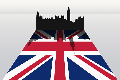 UK politics and government concept: silhouette of parliament buildings and Big Ben with shadow falling onto the Union Jack, UK national flag.