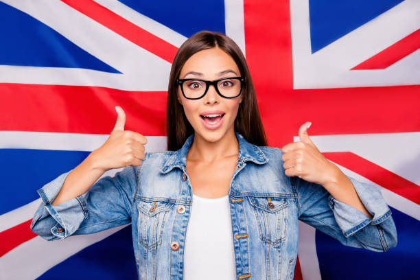 Portrait of cute sweet lovely confident smiling straight-haired Portrait of cute sweet lovely confident smiling straight-haired student lady emigrant wearing spectacles, showing two thumbs up, isolated over Great Britain union jack flag english culture stock pictures, royalty-free photos & images
