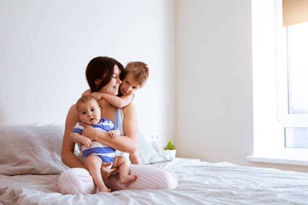 Portrait of mother with two sons in bedroom at home stock photo