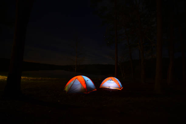 istock Two similar tents lit from within, pitched next to forest lake at night 1096830226